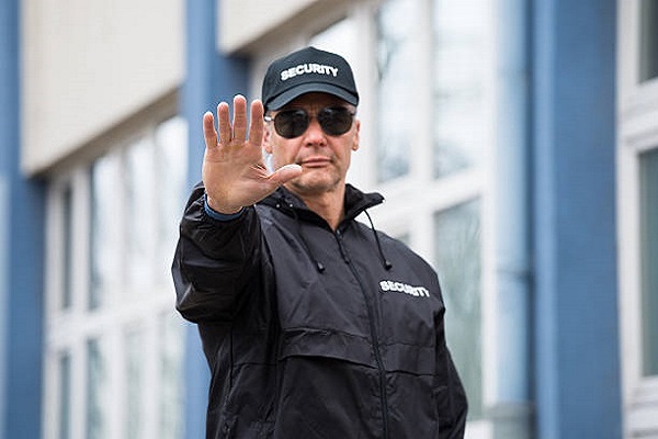 Confident security guard making stop gesture outside building