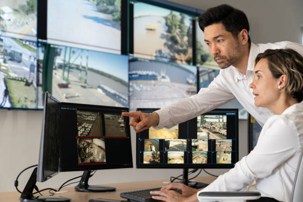 Close-up Of Male Security Guard Talking On Walkie-talkie While Monitoring Multiple CCTV Footage